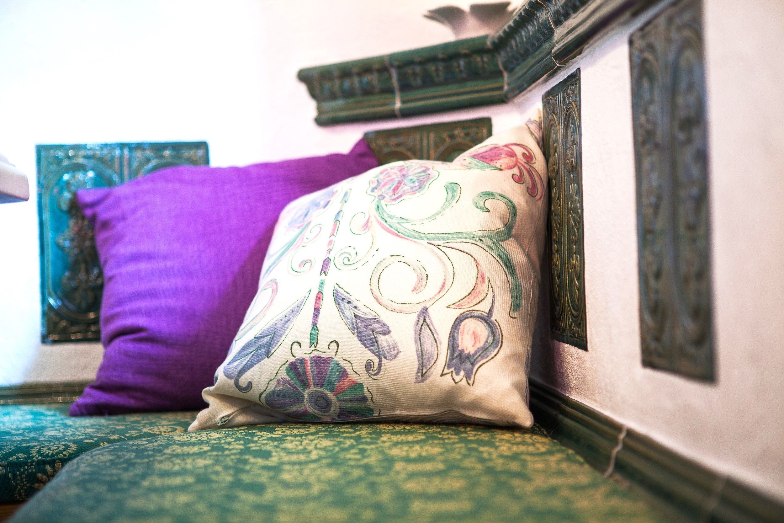 A bed with a decorative pillow and a green patterned bedspread.