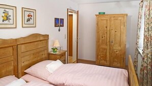 Un dormitorio con cama de madera, mesita de noche, armario y cuadros en la pared.