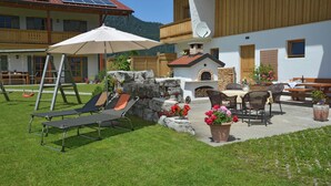 Une terrasse extérieure moderne, dotée d’un fauteuil de relaxation, d’une table avec des chaises et d’une cheminée en pierre.