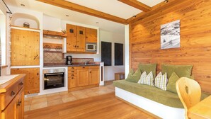 Un intérieur en bois comprenant une cuisine, un coin repas et un canapé avec des coussins.