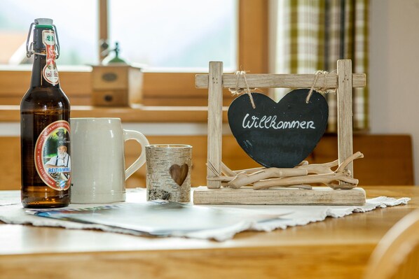 A bottle of beer, a mug, and a sign with "Willkommen" on a wooden stand.