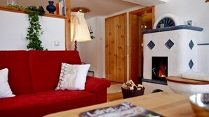 Een gezellige woonkamer met een rode bank, een open haard en een houten tafel.