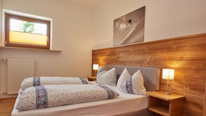 Ein Schlafzimmer mit Bett, Nachttischen, einer Lampe, einem Fenster und einem Bild an der Wand.