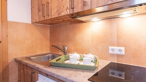 Eine Küche mit Holzausstattung, einem Edelstahlspülbecken, einem eingebauten Herd und einer Schale mit Teekannen und Tassen.