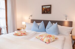 A hotel room with a large bed, two nightstands, a wall-mounted picture, and a window with curtains. - Ferienwohnung (6) (Reit im Winkl)