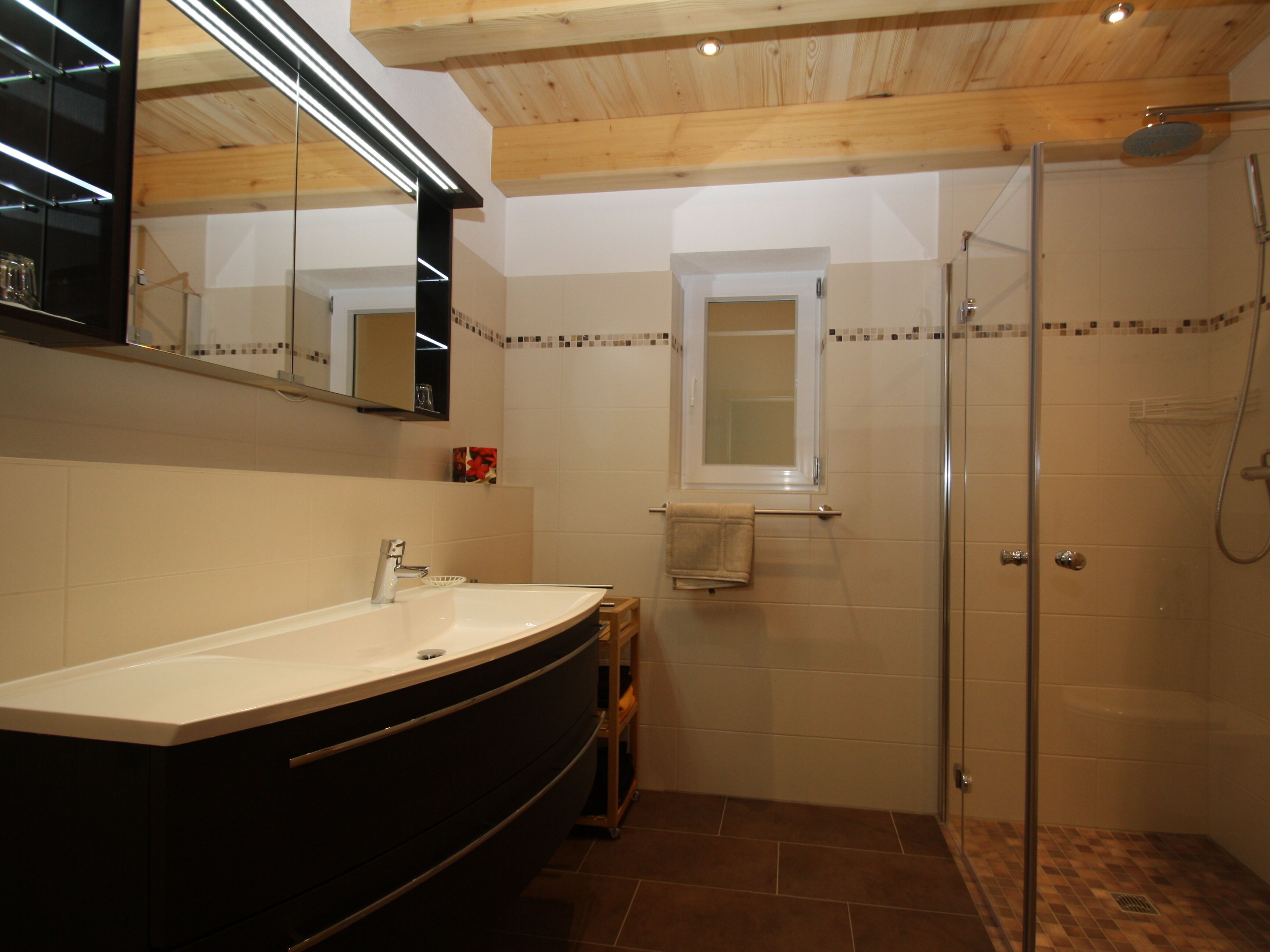 Une salle de bain avec un grand lavabo, un miroir, une douche et une fenêtre.