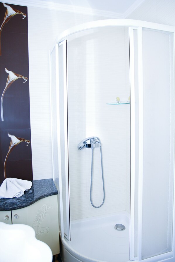A modern bathroom with a glass-enclosed shower, a white sink, and a countertop with a towel.