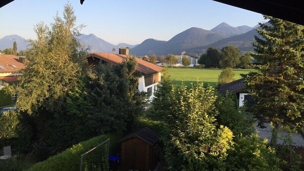 A residential area with houses, a wooden shed, and mountains in the background.