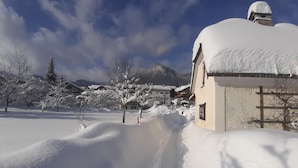 Een besneeuwd dorp met traditionele gebouwen en een berg op de achtergrond.