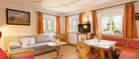A cozy living room with a sofa, a dining table, and a television.