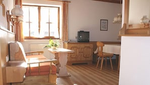 Una sala acogedora con piso de madera, un sofá, una mesa de comedor y un televisor.