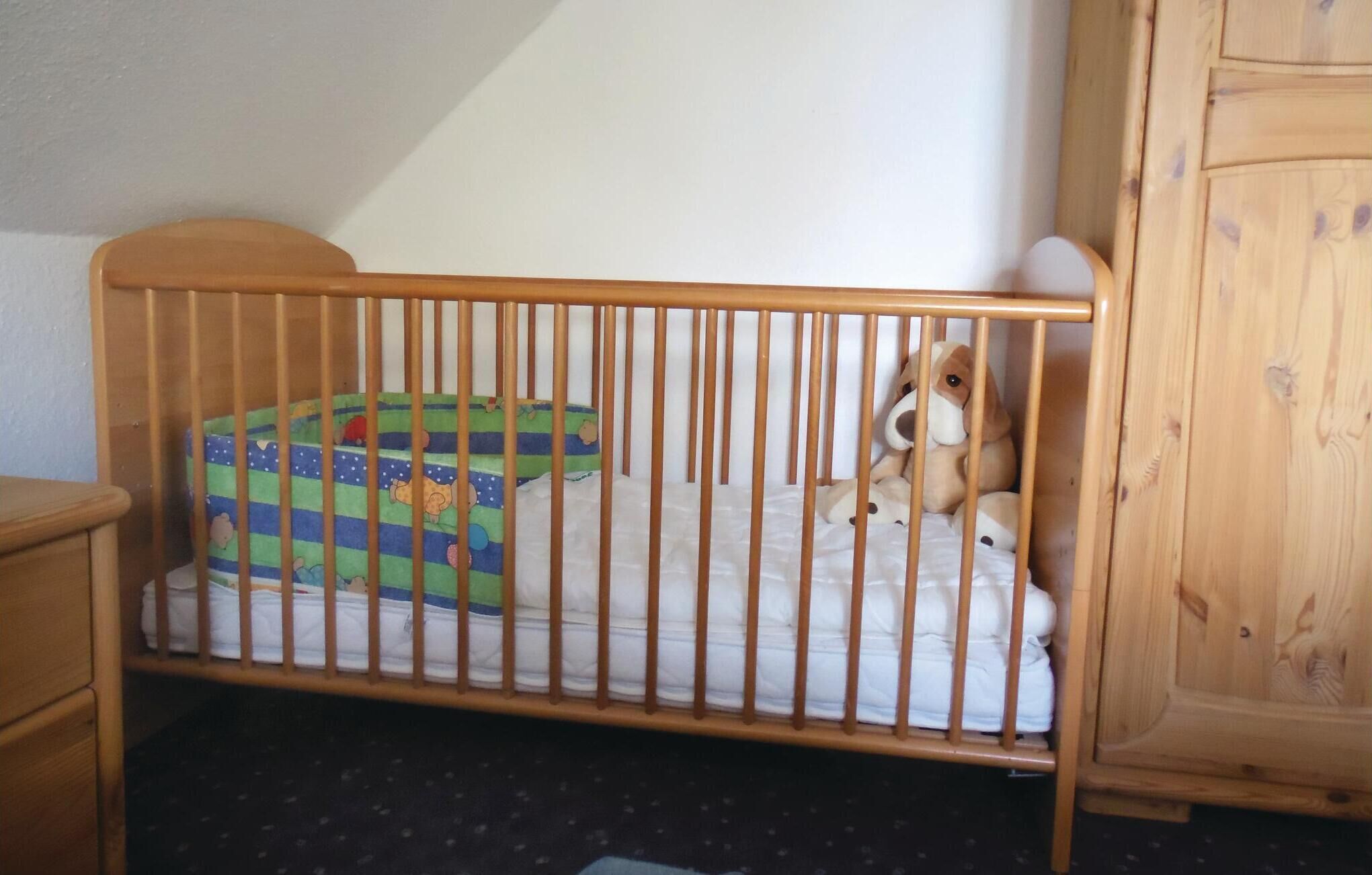 A wooden crib with a colorful mattress and a stuffed animal.