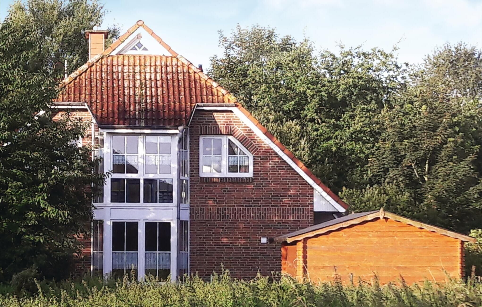 A two-story house with a red-tiled roof, a brick facade, and a wooden extension.