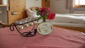 Una stanza con un letto, un comodino con un vaso di fiori e una lampada a parete.