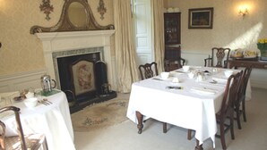 A dining room with a fireplace, a table set for six, and a chandelier. - Kirklands Bed & Breakfast (Melrose)