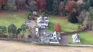 An aerial view of a residential area with multiple houses, a driveway, and surrounding fields. - Kirklands Bed & Breakfast (Melrose)