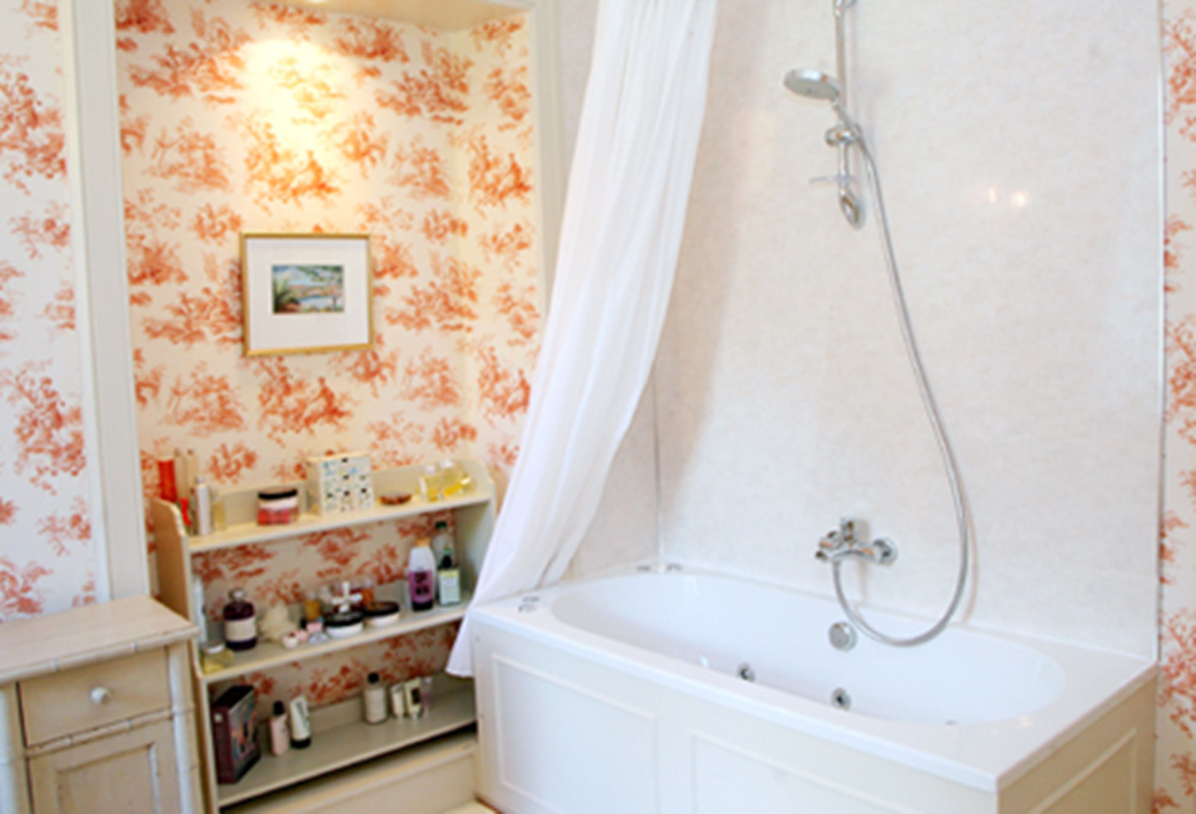 A bathroom with a bathtub, shower, and shelves with toiletries.