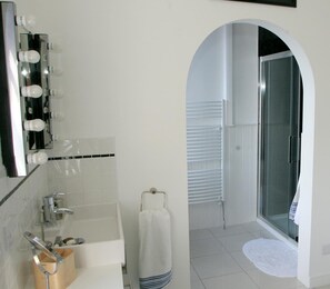 A bathroom with a mirror, lights, a bathtub, a towel rack, and a shower area. - Kirklands Bed & Breakfast (Melrose)