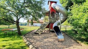 A playground with a slide, a climbing structure, and a picnic area.