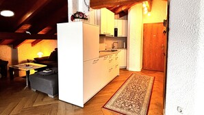 A cozy, rustic interior with a wooden ceiling, a white kitchen island, and a herringbone-patterned wooden floor.