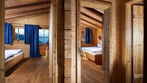 Una cabaña de madera con dos dormitorios, cada uno con cama y ventana con cortinas.