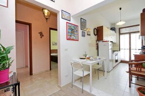 A compact kitchen with a dining area, white cabinets, and a small refrigerator. - La Stazione Del Vaticano (Rome)