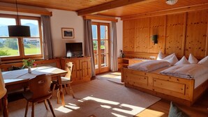 Una cabaña de madera con comedor, televisor, cama con almohadas y vistas al exterior.
