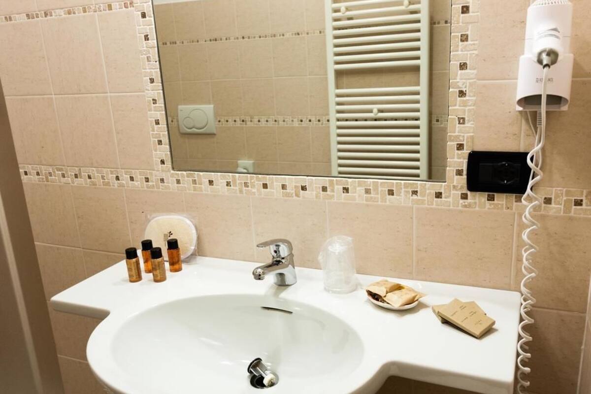 A bathroom with a white sink, a mirror, a towel rack, and a hairdryer.