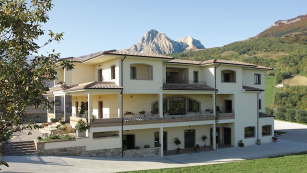 Un edificio de varios pisos con un balcón, una escalera de piedra y una montaña al fondo.