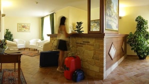 Una sala de estar con chimenea de piedra, dos sillones blancos, una mesita de centro y una planta en maceta.