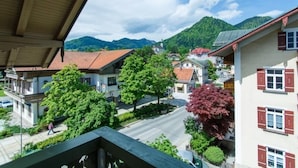 Une rue résidentielle bordée de maisons, d’arbres, avec des montagnes en arrière-plan.