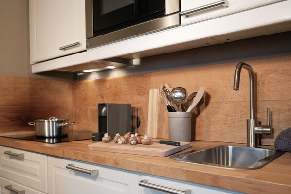 A modern kitchen with stainless steel appliances, a wooden countertop, and a sink. - (1) Ferienwohnung 1 mit eigenem Garten (Reit im Winkl)