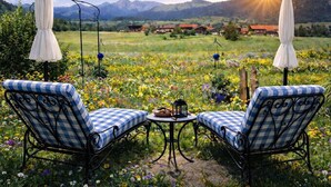 Un jardín con dos sillones a cuadros, una mesa y sombrillas.