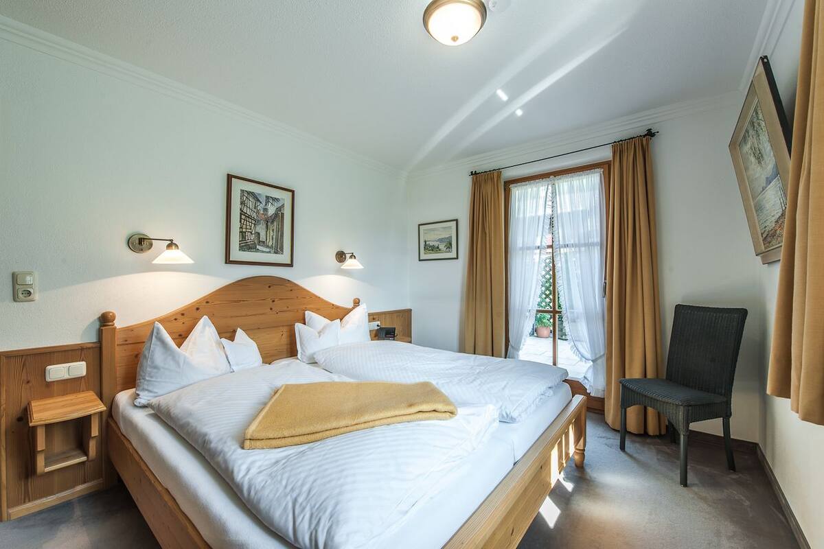 A neatly made bed with white linens, a wooden headboard, and a bedside table with a lamp.