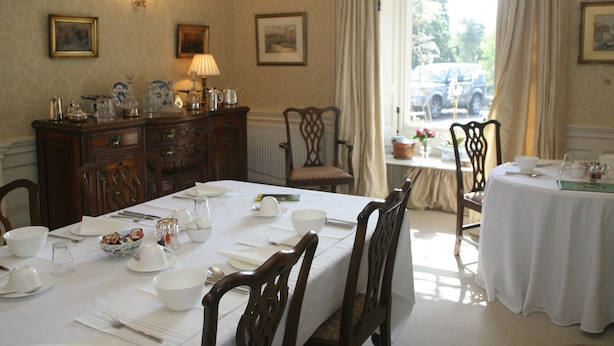 A dining room with a long table set for a meal, surrounded by wooden chairs. - Kirklands Cottages (Melrose)