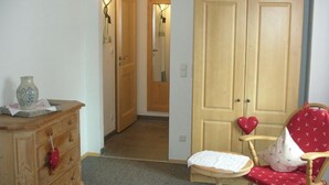 Een kamer met een houten dressoir, een stoel met een rode kussen en een grote kast.
