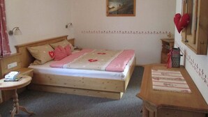 Een gezellige slaapkamer met een houten bed, een klein nachtkastje, een wandlamp en een schilderij.