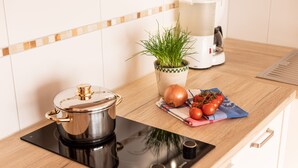Eine Küche mit Herd, Topf, Kaffeemaschine, Pflanze und frischen Tomaten auf der Arbeitsfläche.