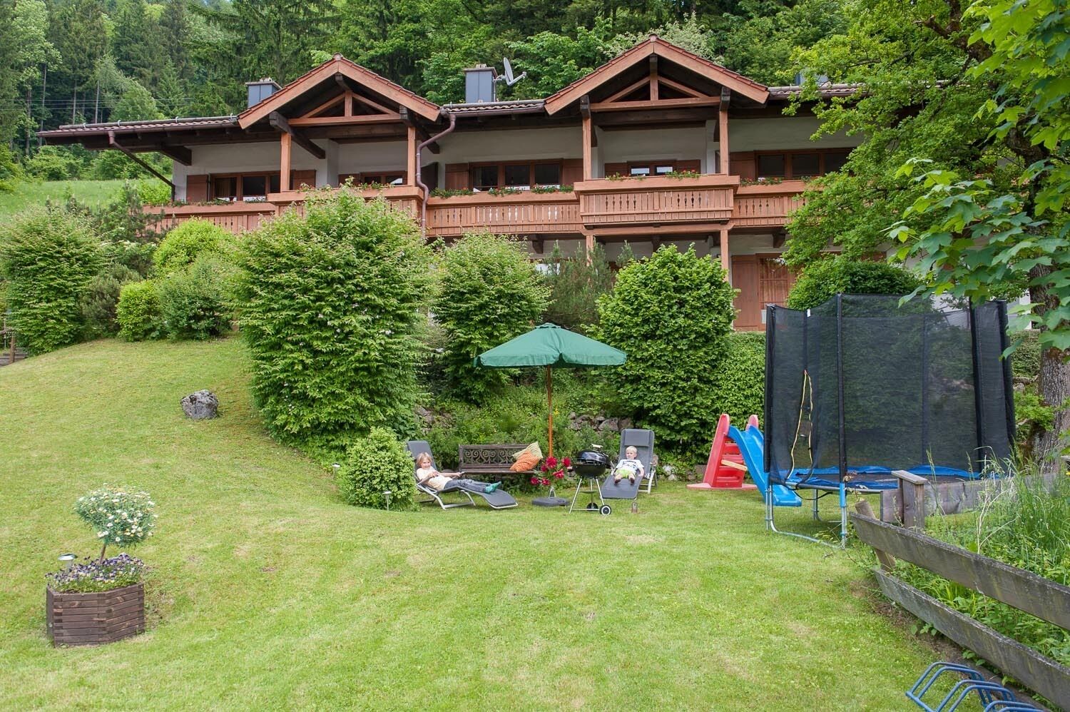 Eine zweistöckige Lodge mit Balkon, umgeben von üppiger Vegetation und einem gepflegten Rasen.
