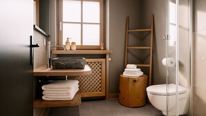 Un baño moderno con tocador de madera, inodoro y cabina de ducha de vidrio.