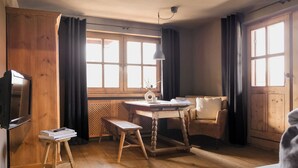 Una habitación acogedora con muebles de madera, una mesa, un banco, un sofá y un televisor.