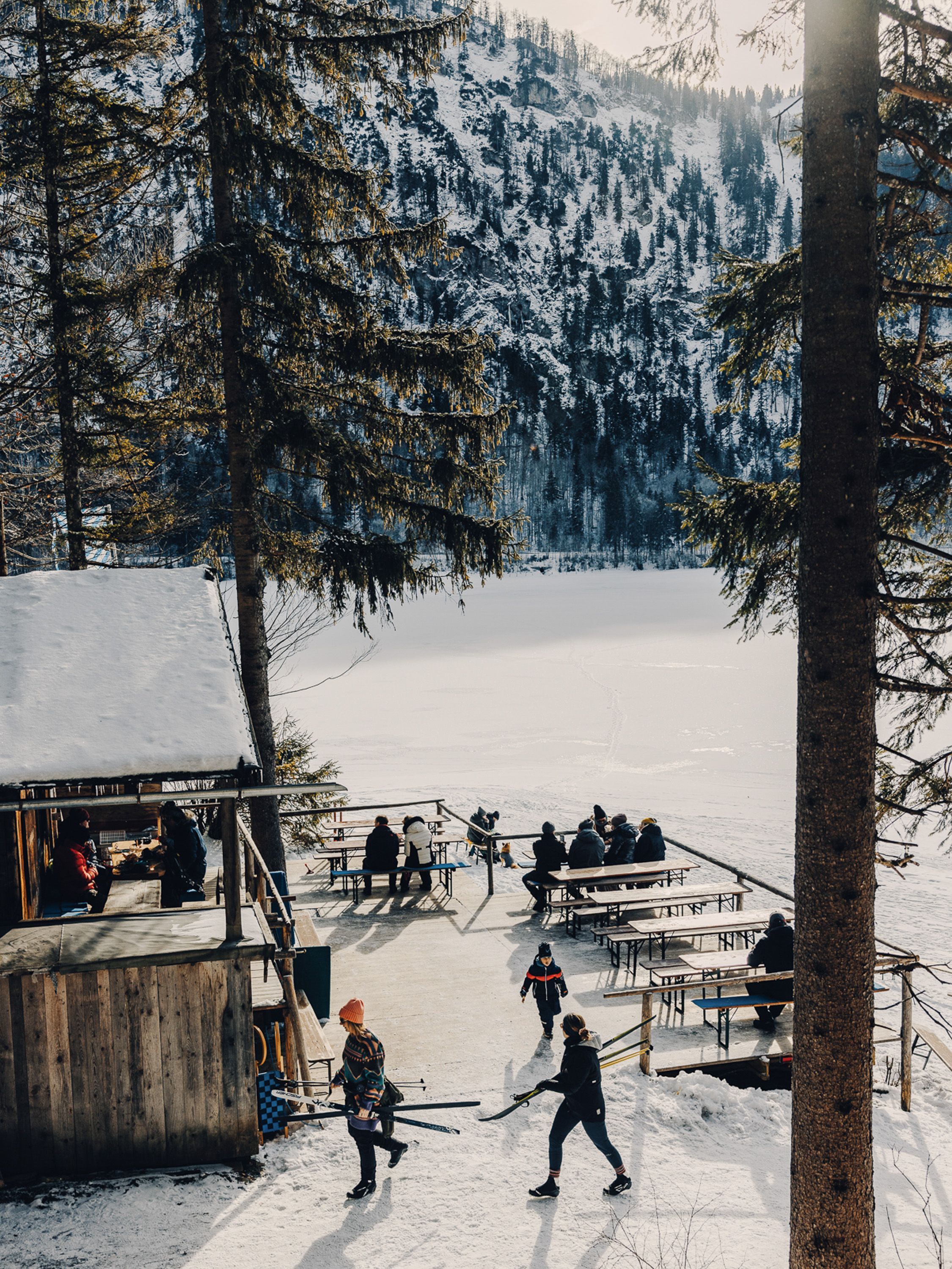 A snowy outdoor area with benches and tables, surrounded by trees and a snow-covered landscape.