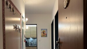 A hallway with a colorful rug, a kitchen in the background, and a door with a keyhole. - Ferienwohnung "Beste Laune" (Reit im Winkl)