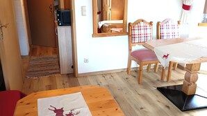 Een gezellig eetgedeelte met houten meubels, een tafel met een placemat met paardendesign, en een spiegel boven een houten kastje.
