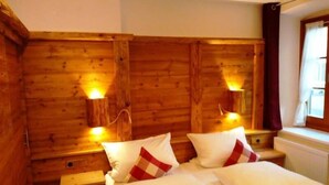 Une chambre rustique en bois, avec un lit, deux tables de chevet et des lampes fixées au mur.