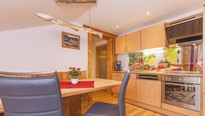 Une cuisine moderne avec des meubles en bois, un four encastré et un coin repas comprenant deux chaises et une table.