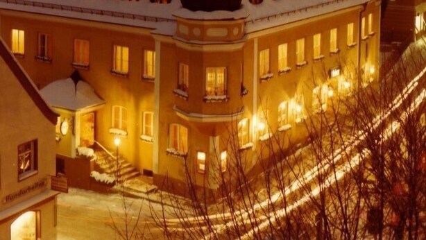 Suuri, monikerroksinen rakennus, jonka lumipeitteiset katot ja valaistut ikkunat viittaavat talviseen ympäristöön.