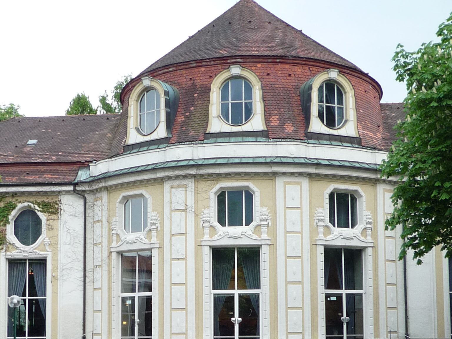 A historic building with a curved facade, multiple windows, and a distinctive corner tower.