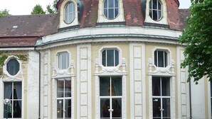 Un bâtiment historique à la façade incurvée, doté de nombreuses fenêtres et d’une tour d’angle remarquable.