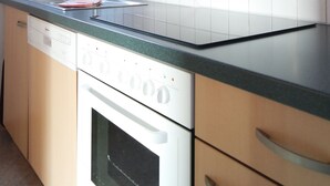 Une cuisine moderne avec des meubles de couleur bois clair, un évier en acier inoxydable et un lave-vaisselle encastré.